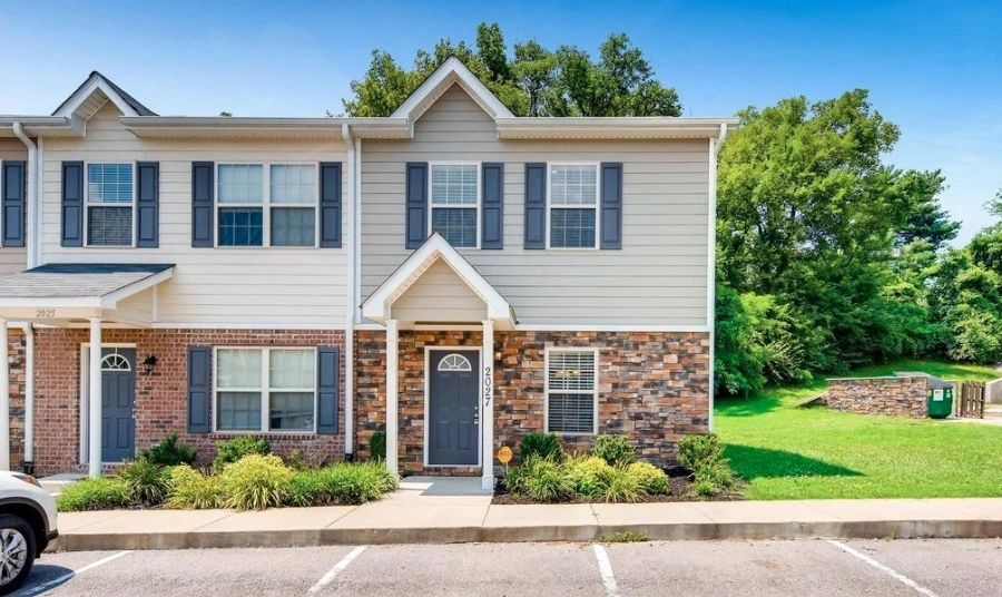 Contemporary townhouse exterior featuring brick and siding, with a landscaped front yard. Ideal for real estate listings or property showcases.